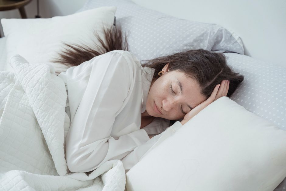 Een persoon slaapt comfortabel met een kniekussen voor een betere slaaphouding en ondersteuning.